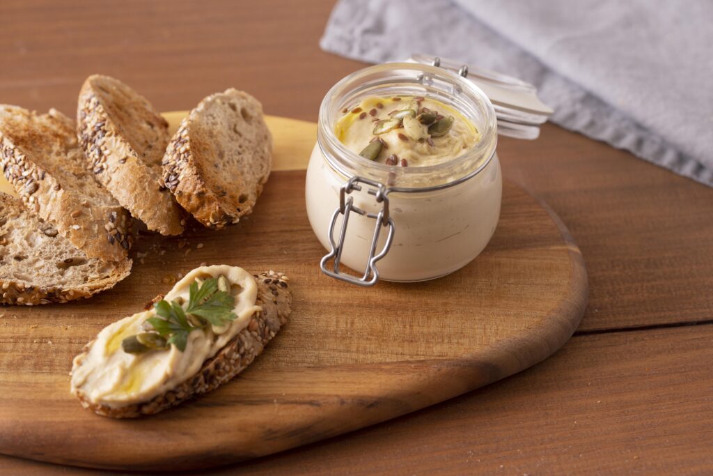 A bowl of creamy old-fashioned pimento cheese spread garnished with fresh parsley, served with crackers and fresh vegetables.