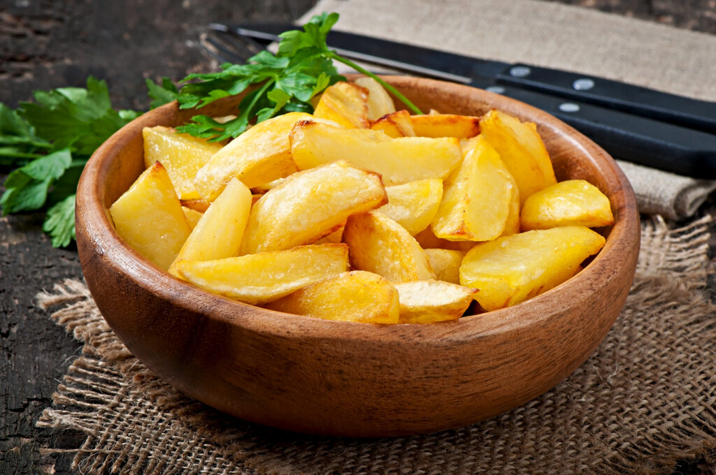 Smothered potatoes in a skillet, garnished with fresh parsley, showing creamy texture and golden-brown onions.