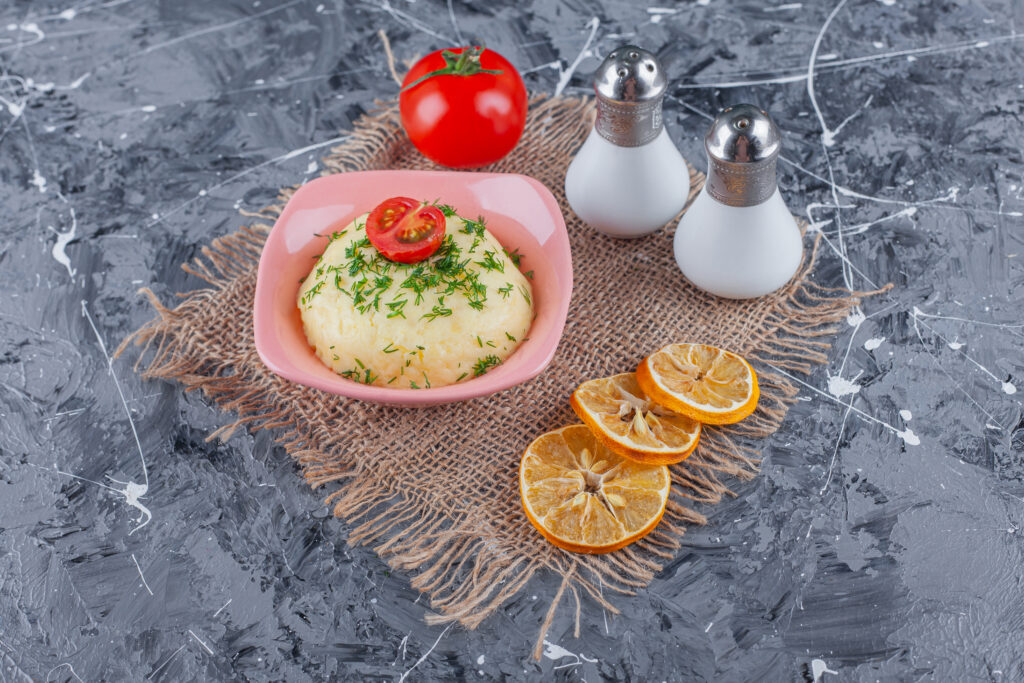 A bowl of creamy Hellmann's potato salad made with boiled potatoes, mustard, and seasonings, garnished with fresh herbs.